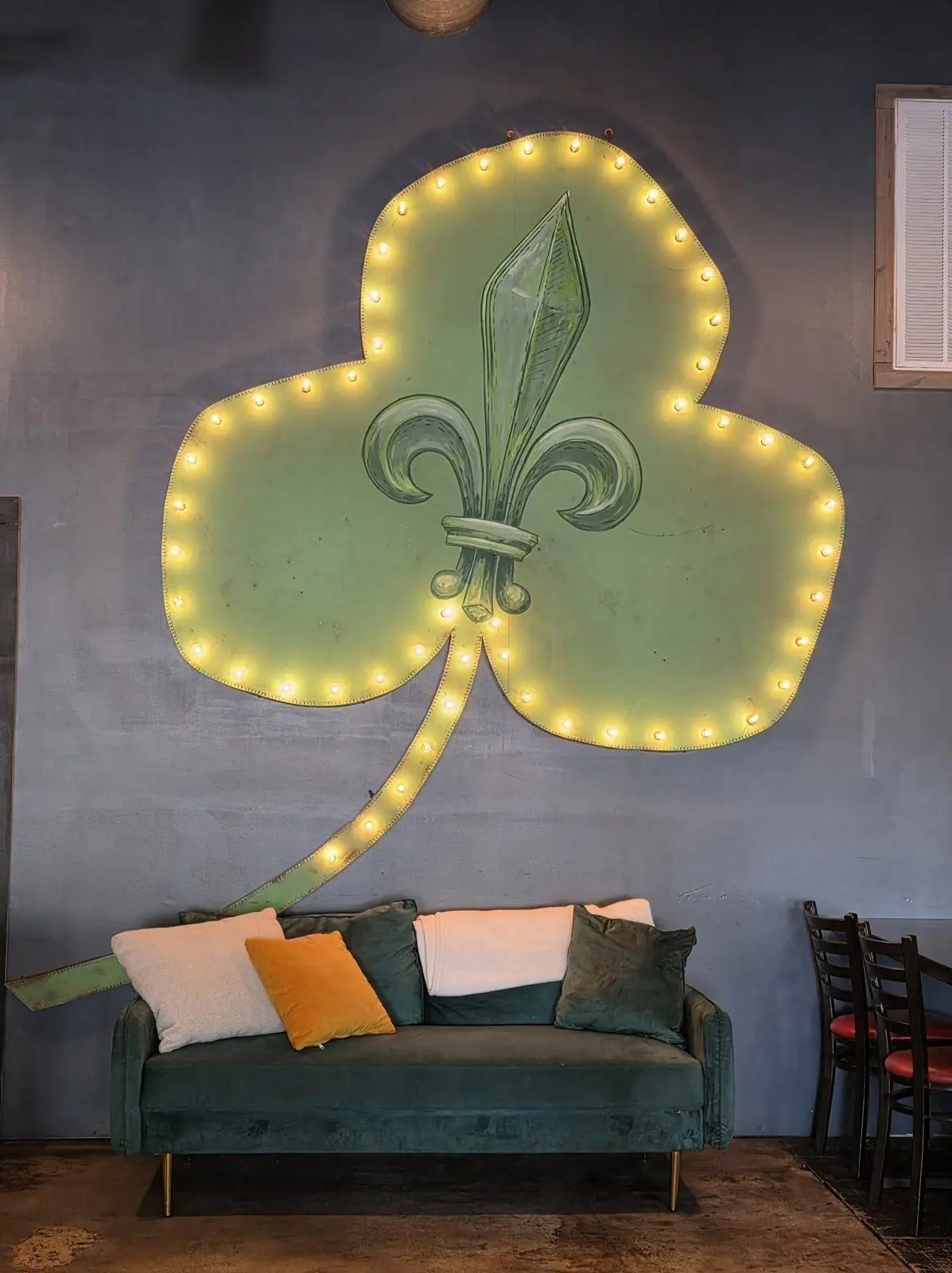 The lit shamrock and fleur-de-lis sign inside Nola's Clover