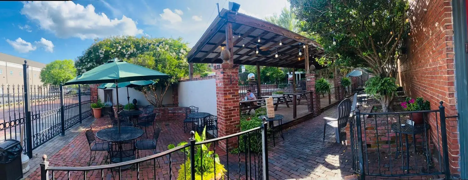 The brick courtyard with umbrellas, a covered pavilion, and string lights