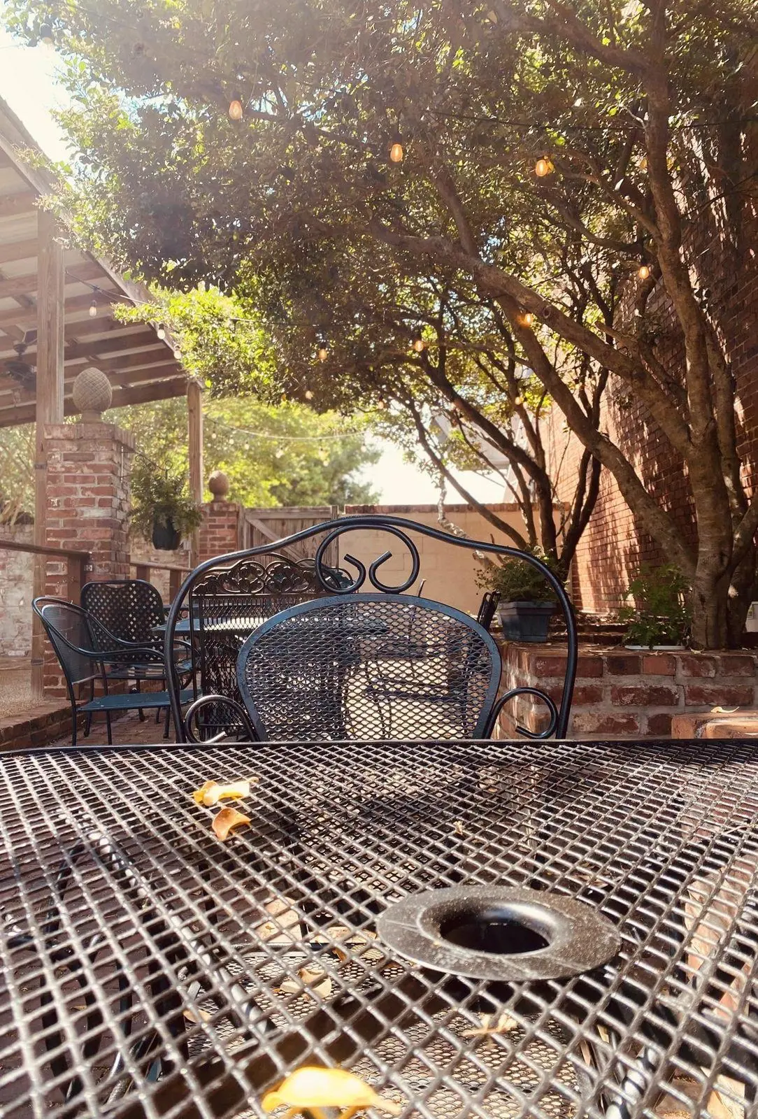 Wrought-iron tables beneath trees and string lights