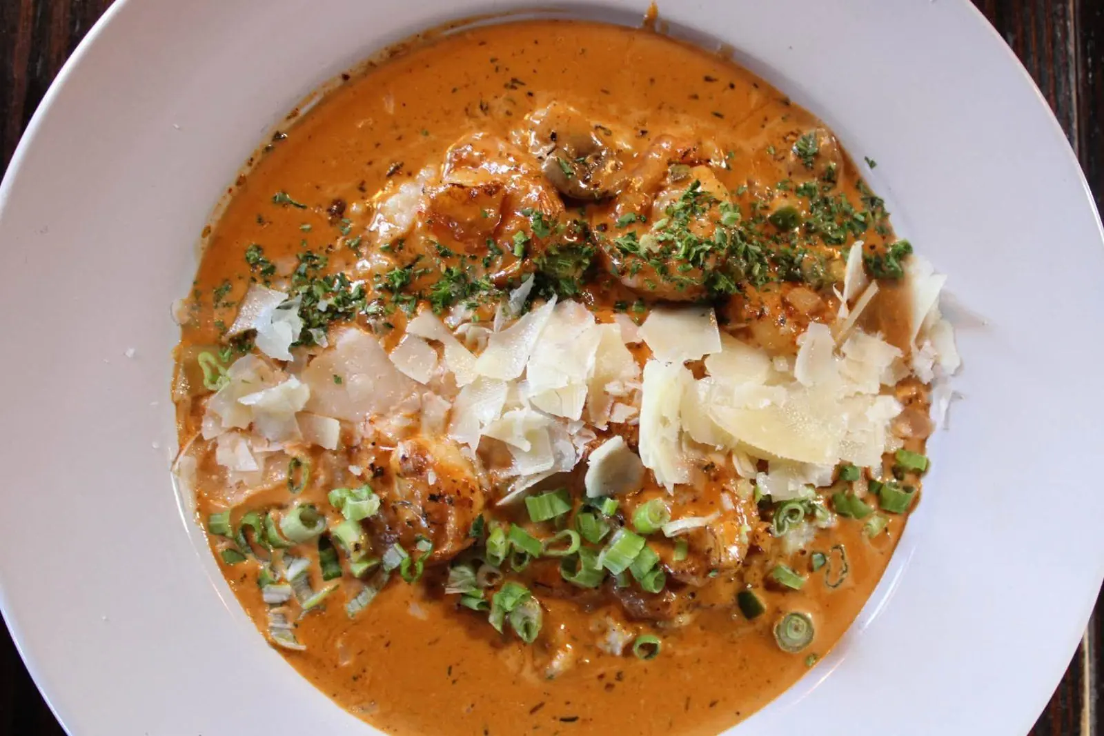 Shrimp and grits in creole cream sauce topped with shaved parmesan and green onion